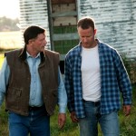 Two farmers walking in the grass.