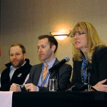 Three people sitting at a table for a conference.