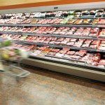woman shopping near a meat display in a grocery store
