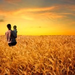 man in wheat field with boy