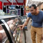 Male customer at a market shopping for meat at the butcher's stall pointing at retail display