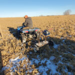Bootsman uses a quad to roll and unroll aircraft cable for electric fence.