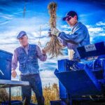 Axel Diederichsen and Travis Sander threshing wheat.