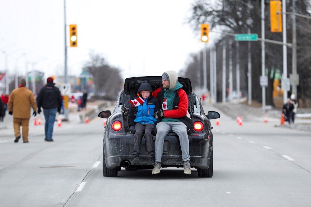 A man and a child ride away from a protest site at Windsor, Ont. on Feb. 12, 2022. (Photo: Reuters/Carlos Osorio)
