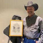 Kelly Feige poses with a portrait of his father, John Feige.