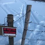 A no-trespassing sign on pastureland in northwestern Saskatchewan, taken in February 2022. Note the snowmobile tracks and cut wire.