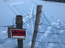 A no-trespassing sign on pastureland in northwestern Saskatchewan, taken in February 2022. Note the snowmobile tracks and cut wire.