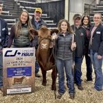 group of people standing beside a cow at an awards presentation