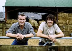 Famer and His Son Standing Side by Side Leaning on a Gate