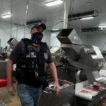 An agent passes meat being prepared during a raid by U.S. Immigration and Customs Enforcement (ICE) at a Glenn Valley Foods meat production plant in Omaha, Nebraska, U.S. June 10, 2025 in a still image from video. Photo: U.S. Immigration and Customs Enforcement/Handout via Reuters.
