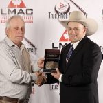 Casey Lawes receiving the 2025 Canadian Livestock Auctioneering Championship buckle from Travis Hunter.