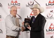 Casey Lawes receiving the 2025 Canadian Livestock Auctioneering Championship buckle from Travis Hunter.