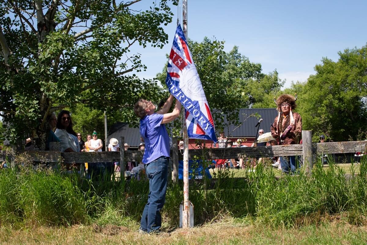 Brenda Bohmer raises the Treaty 6 flag while Elder Bert Bull watches. Part of the Alberta launch of the Treaty Land Sharing Network at Bohmer's farm near Bawlf, Alta. Photo: Valerie Zink