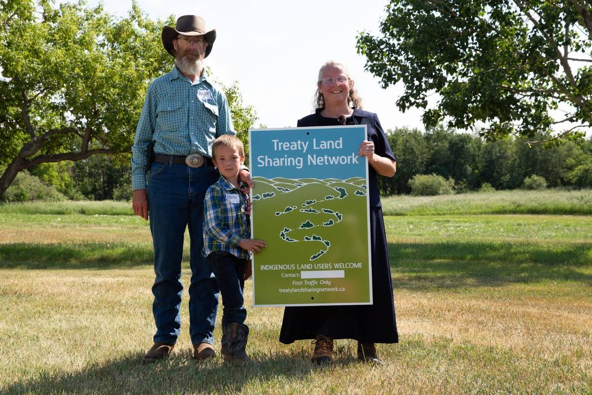 Ralph, Kevin and Elizabeth Holt hold a sign indicating the land they manage is part of the Treaty Land Sharing Network. Photo: Valerie Zink