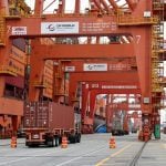 A truck carries a container near a cargo ship bound for Japan at the Centerm container ship terminal at the Port of Vancouver in Vancouver, British Columbia, Canada August 3, 2025. REUTERS/Chris Helgren