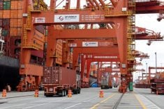 A truck carries a container near a cargo ship bound for Japan at the Centerm container ship terminal at the Port of Vancouver in Vancouver, British Columbia, Canada August 3, 2025.  REUTERS/Chris Helgren