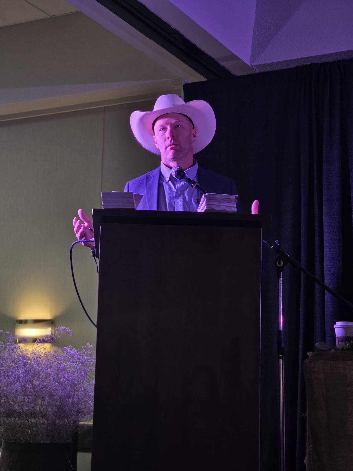 Canadian Cattle Association president Tyler Fulton in a white cowboy hat addresses an audience from a podium at a cattle industry event. Photo: Miranda Leybourne